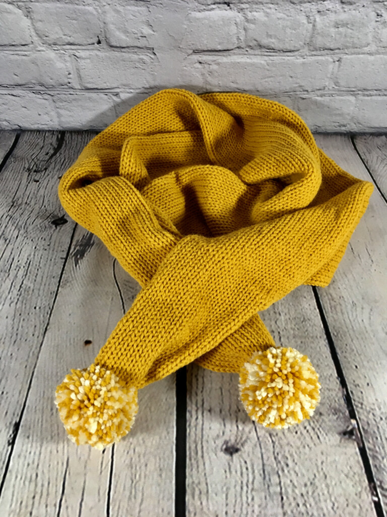 Knitted scarf with pom poms